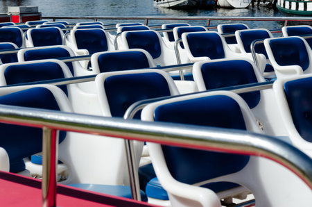 Angled rows of symmetrical white and blue deck chairs on a tour boat.の写真素材