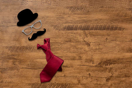 representation of father's day with top hat, glasses, mustache and tie. Isolated over wooden table, with copy space and text.の写真素材
