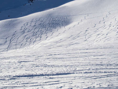 Carver and snowboarder traces in the fresh deep snow in a high mountain region of the Engadineの写真素材