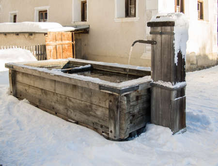 A well made of wood  in a typical mountain village in the Engadine, Switzerlandの写真素材