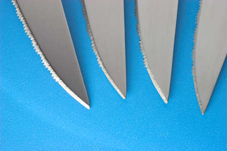 Four steak knifes on blue backgroundの写真素材