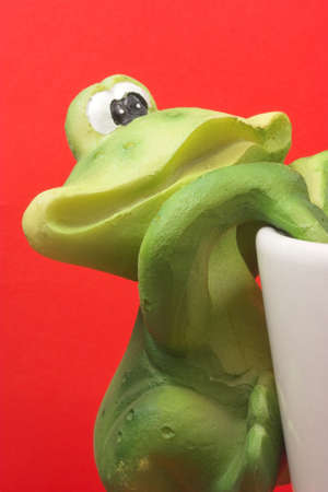 Frog climbing coffee cupの写真素材