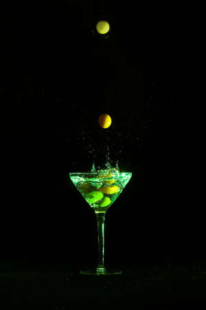 Olives dropping into martini glass, stop motionの写真素材