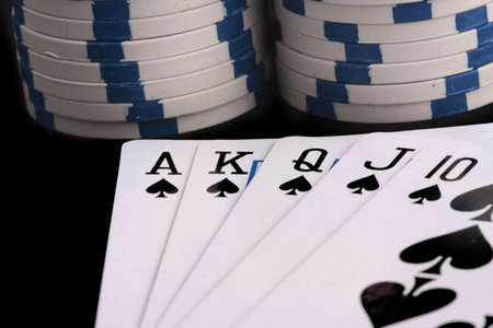 Royal flush on black background with stacked chips