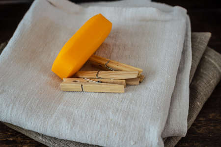 Stack of clean linen towels, clothespins and natural soap on tableの写真素材