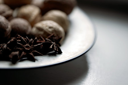 Blurred background with defocused walnuts and anise stars in vintage plate. Close up