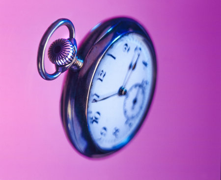 Old pocket watch floating on a pink background