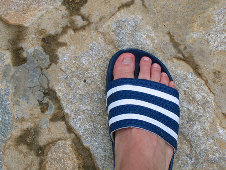Right foot in flip-flops on stone floor
