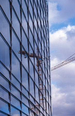 Modern glass facade with construction craneの写真素材