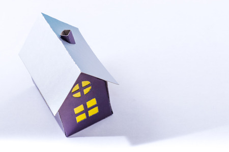 purple cardboard house with yellow windows isolated on white background.Concept of a good investmentの写真素材