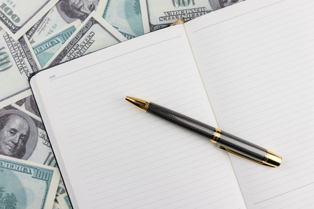 Notebook with pen  on dollar bills backgroundの写真素材