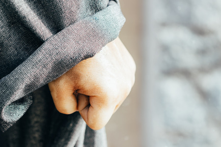 caucasian hand in coat clenched in fist close-up. Symbol of unbreakable willの写真素材