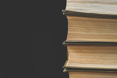 Close-up vertical stack of books background with copyspace toned
