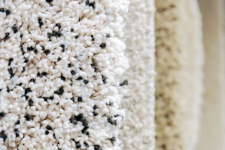 Carpets of shades of gray and white are hanging for sale with copy space.の写真素材