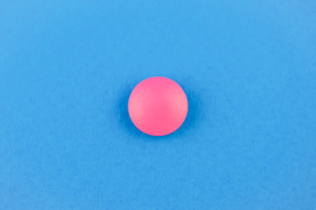 Pink pill on blue background. The concept of universal treatment. Panacea. Close up.の写真素材