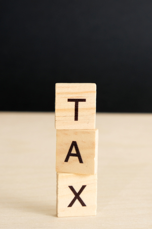 The word "tax" on a wooden and black background with copy space. Vertically. Mock up.の写真素材