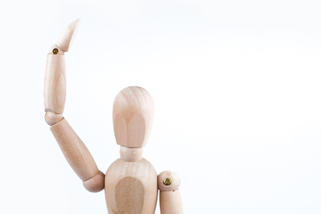 The concept of joyful greeting. Wooden mannequin raised his hand on a white background. Copy space.の写真素材