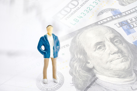 The concept of a successful banker. Toy man model on the background graphics with US dollars.の写真素材