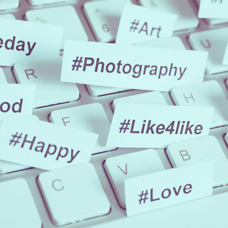 Popular hashtags printed on white paper inserted into the keyboard, square format, toned.
