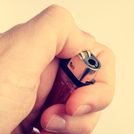 Hand holding a gas lighter, square format, toned.の写真素材