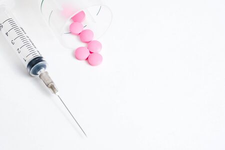 The concept of weekly treatment with the use of pills and injections. Syringe with a container and pink pills. Place for text.の写真素材