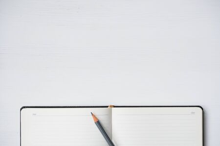 Notebook with pencil on white wooden table. Copy space. Top view.の写真素材