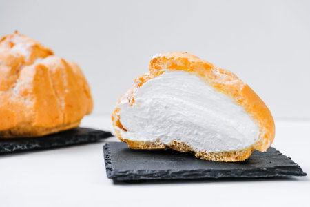 sweet buns in a cut with jam and cream on a shale dishes and wooden background. Close up.