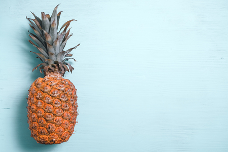 Ripe pineapple left side on a blue wooden table. Copy space. top view.の写真素材