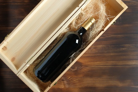 A dark expensive bottle of wine in a wooden box on a wooden background. Top view.の写真素材