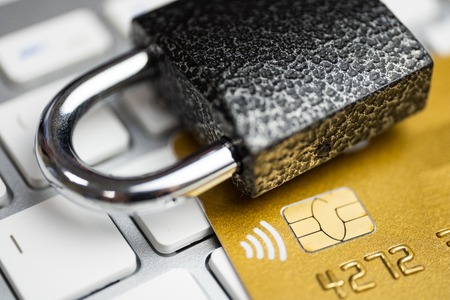 Concept of security of electronic payment. Lock on gold credit card and white keyboard. Close up.の写真素材