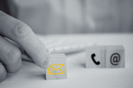 A man holds a cube with the image of a letter on the background of the phone and email with his...