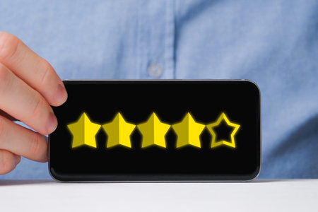 A man in a shirt abstractly shows a rating of four out of five stars in a smartphone. good mark....