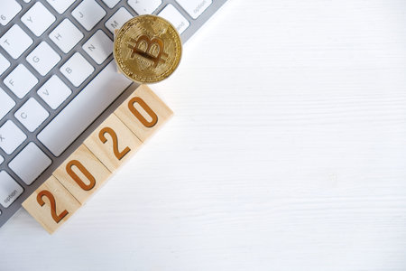 Bitcoin with numbers 2020 on wooden cubes on keyboard with white background. The success of...