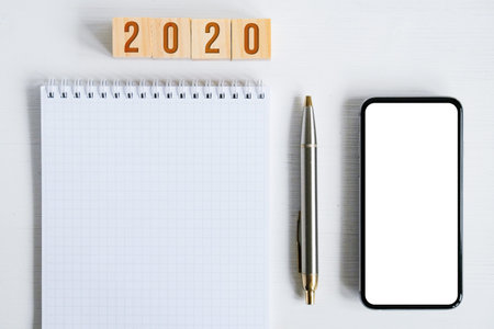Mock up of smartphone, blank sheet of spiral notebook, metal fountain pen, wooden cubes with numbers...