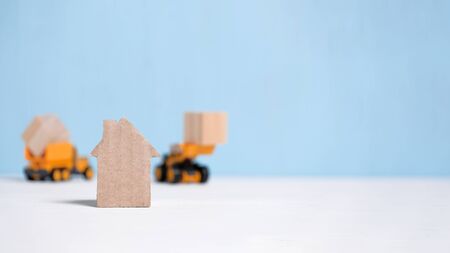 Abstract cardboard house next to construction equipment. The concept of the start of construction. Close up. Copy space.の写真素材