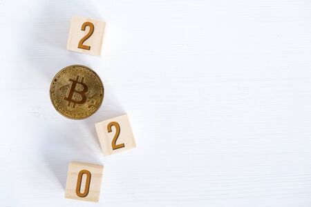 Bitcoin with numbers 2020 on wooden cubes on a wooden background. The success of cryptocurrency in the new year. Flat lay. Copy space.の写真素材