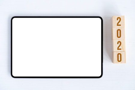 Figures 2020 on cubes and a white wooden background. Tablet with mock up. Flat lay. Close up.