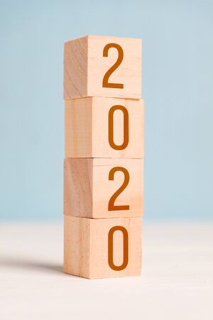 Figures 2020 on wooden cubes on a blue background. The concept of changing the year. Close up. Vertical.の写真素材