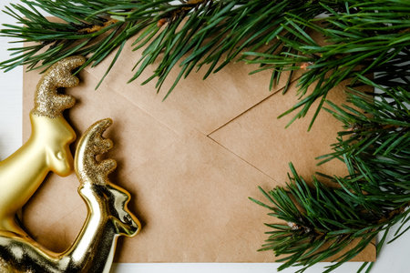Craft envelope with a branch from the Christmas tree with a golden toy deer. Flat lay, close up....