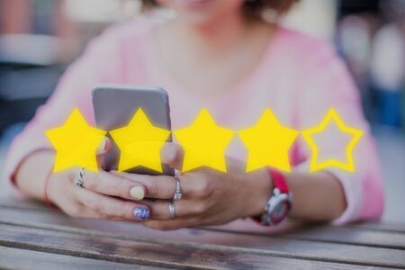 The concept of evaluation, rating on the Internet. Four out of five stars on the background of a girl with a smartphone.の写真素材