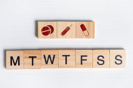 The concept of taking medicines and injections of antibiotics on schedule - days of the week. Wooden squares with icons - tablets, capsule, syringe and letters. Close up.の写真素材
