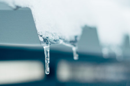 The concept of cooling is fast. Blue toning. An icicle with snow on the roof. Close up.