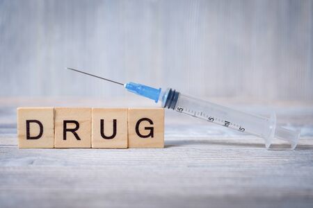 A syringe for drugs on wooden cubes with letters. Close up.の写真素材
