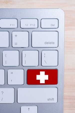 The concept of medical care online. Cross on the keyboard button. Top view. Vertical. Close up.の写真素材