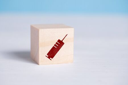 Red syringe sign on a wooden cube. Close up.の写真素材