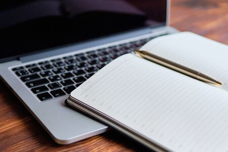 Diary on a laptop on a white wooden background. The concept of new tasks for the day. close up