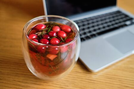 Delicious red tea next to a laptop on a wooden table in a cafe. Close up.の写真素材