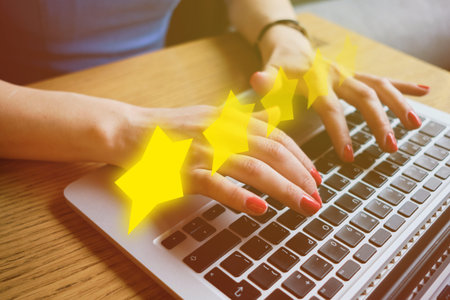 Girl is typing on the keyboard. Online assessment concept. Abstract yellow stars as a rating. Close...