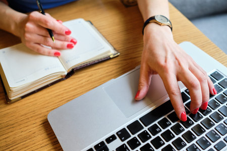 Girl girl working with a diary and laptop in a cafe. Close up.の写真素材