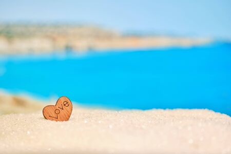 Beautiful blurred view of the beach with a wooden heart in the sand. The concept of a favorite place to travel. Close up.の写真素材